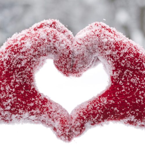 Woman making heart symbol with snowy hands